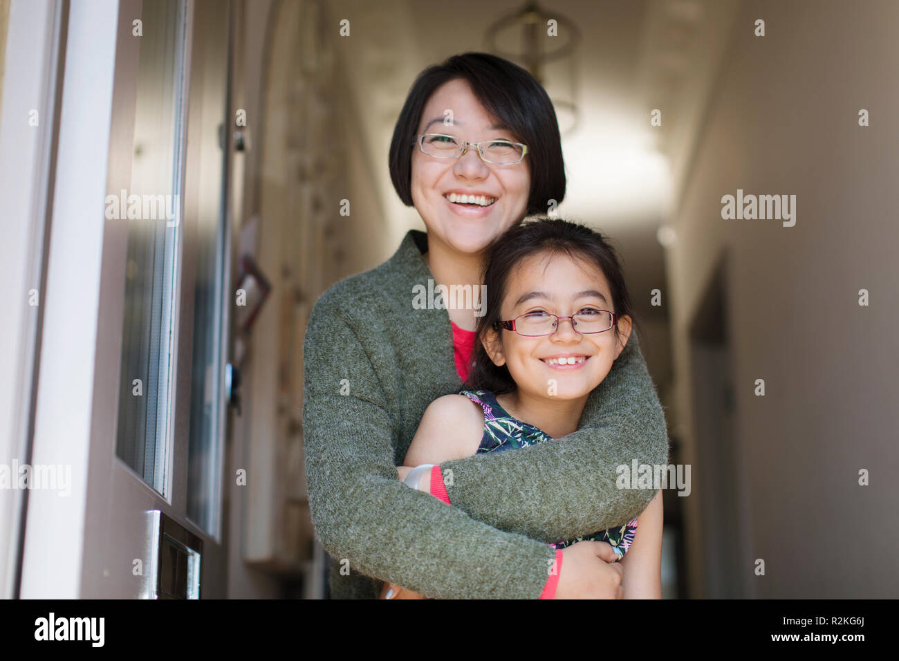 Portrait happy, affectionate mother and daughter hugging in doorway Stock Photo
