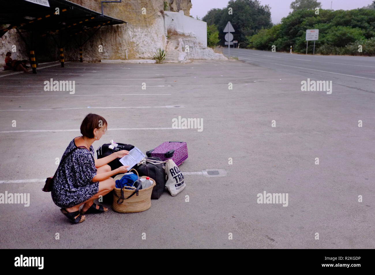 A female tourist waiting by the side of a road in Spain for a bus. Stock Photo