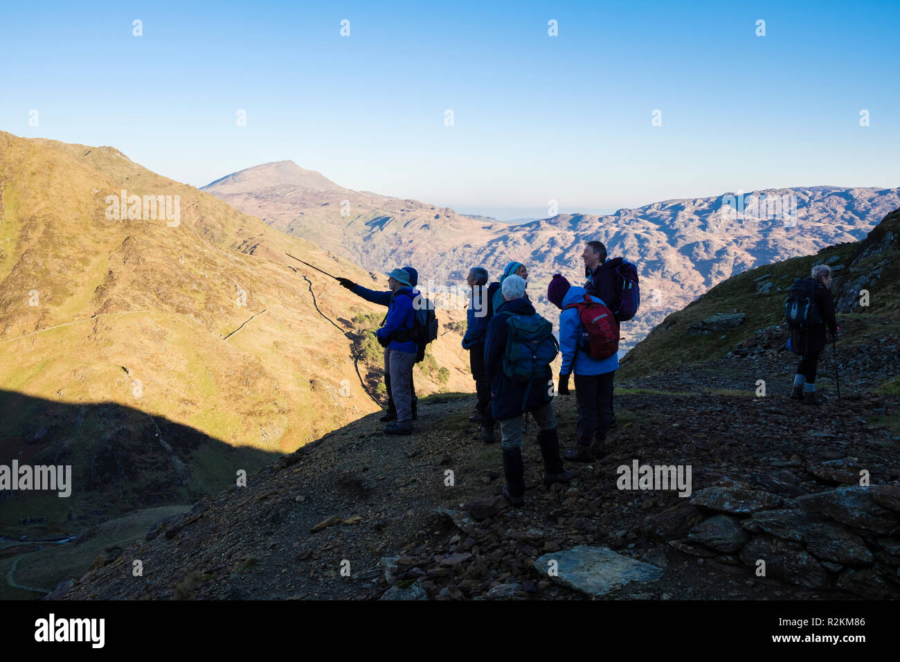 Hikers looking at scenic view on Yr Aran mountainside above Cwm Llan in Snowdonia National Park on clear winter day. Bethania Gwynedd Wales UK Britain Stock Photo