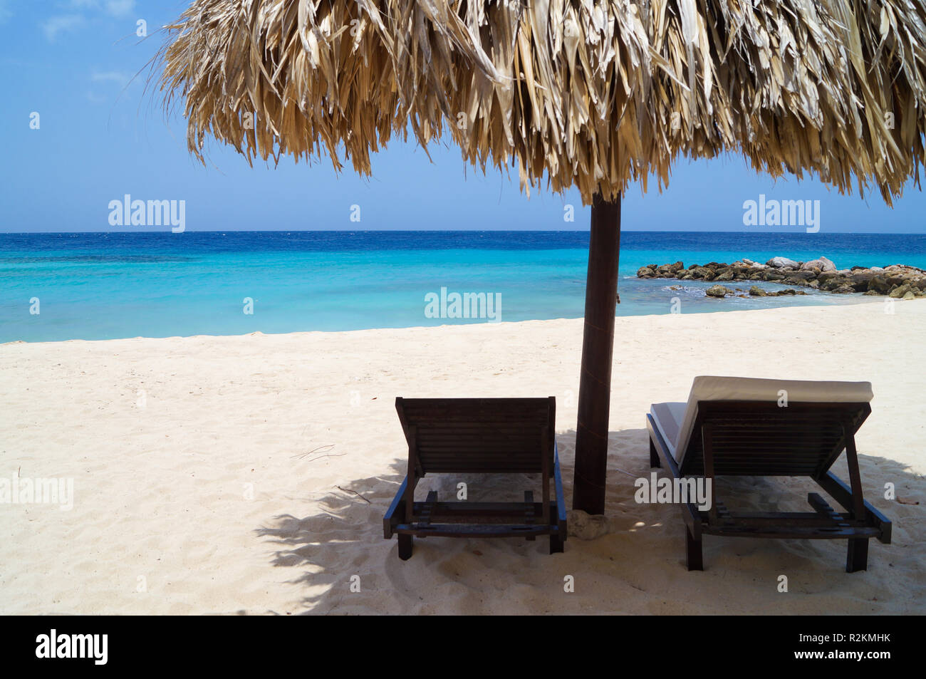 Tiki hut on the beach with white sand and blue water. Paradise on Curacao. Stock Photo