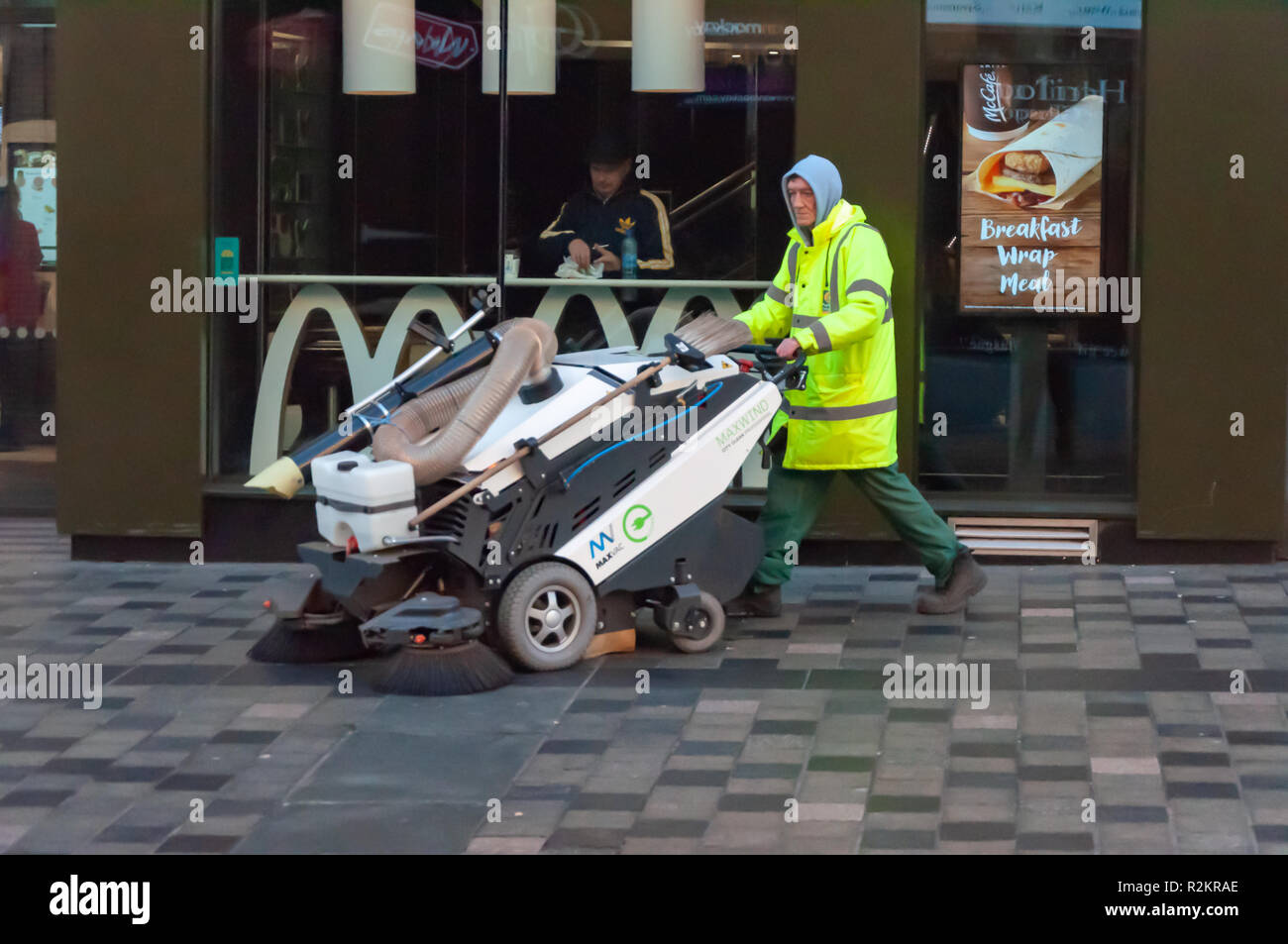 A male Council street cleaner wearing a Hi Vis Jacket and a hoodie using the Maxvac Maxwind pavement sweeper on Sauchiehall St, Glasgow, Scotland, UK Stock Photo