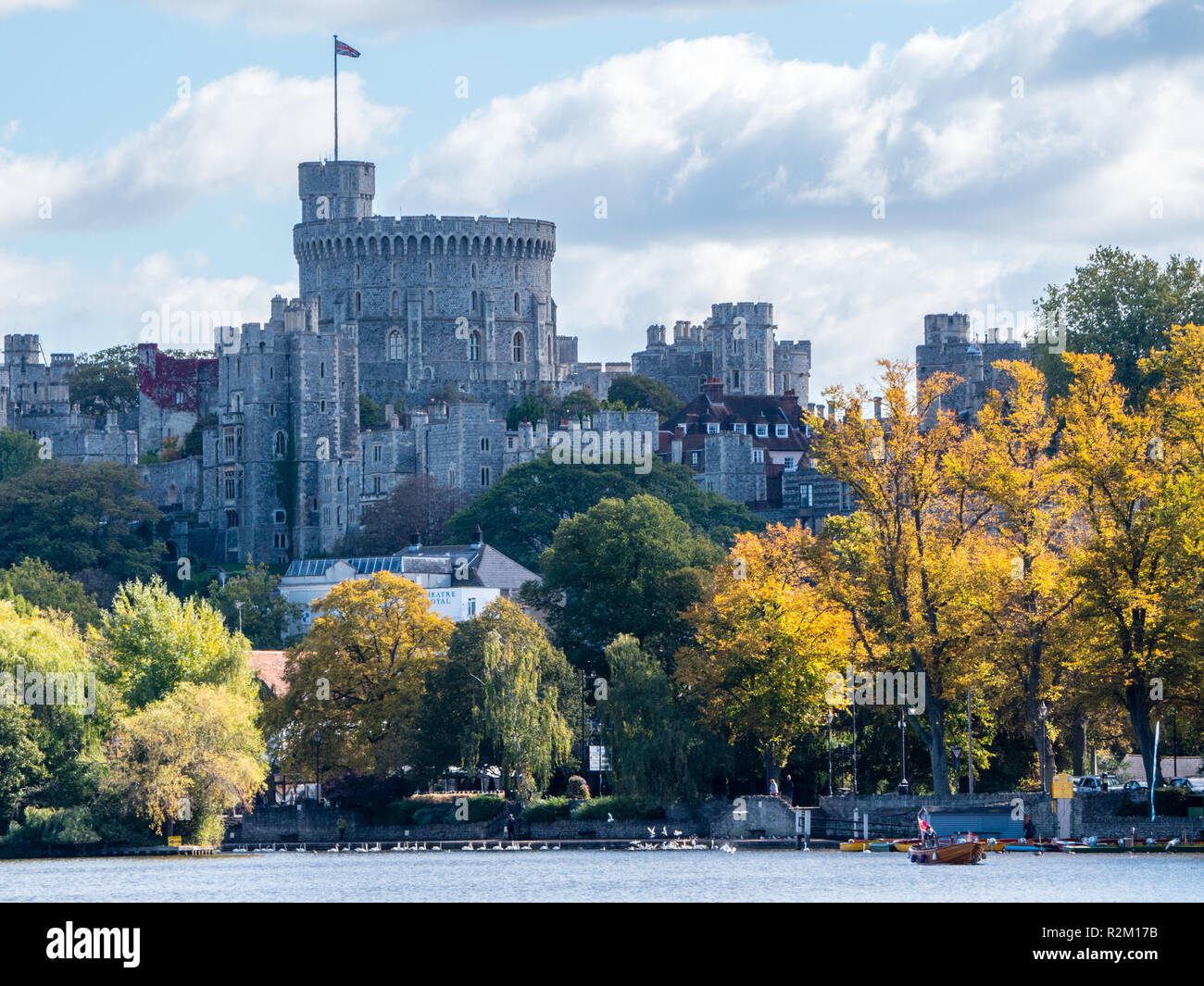 Small Launch with Union Jack Flag, View of Windsor Castle Across River Thames with Autumn Trees, Windsor, Berkshire, England, UK, GB. Stock Photo