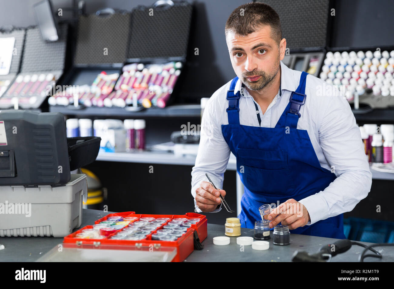 Focused male worker picking up color of fibers for car upholstery in auto repair shop Stock Photo
