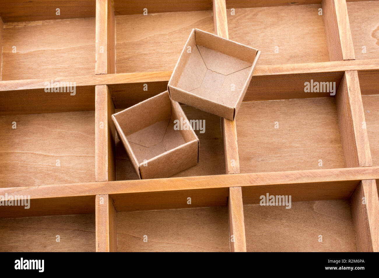 Open cardboard box inside a wooden box with compartments Stock Photo