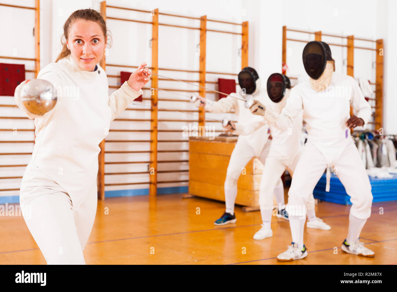 Sporty young female fencer practicing fencing technique in training