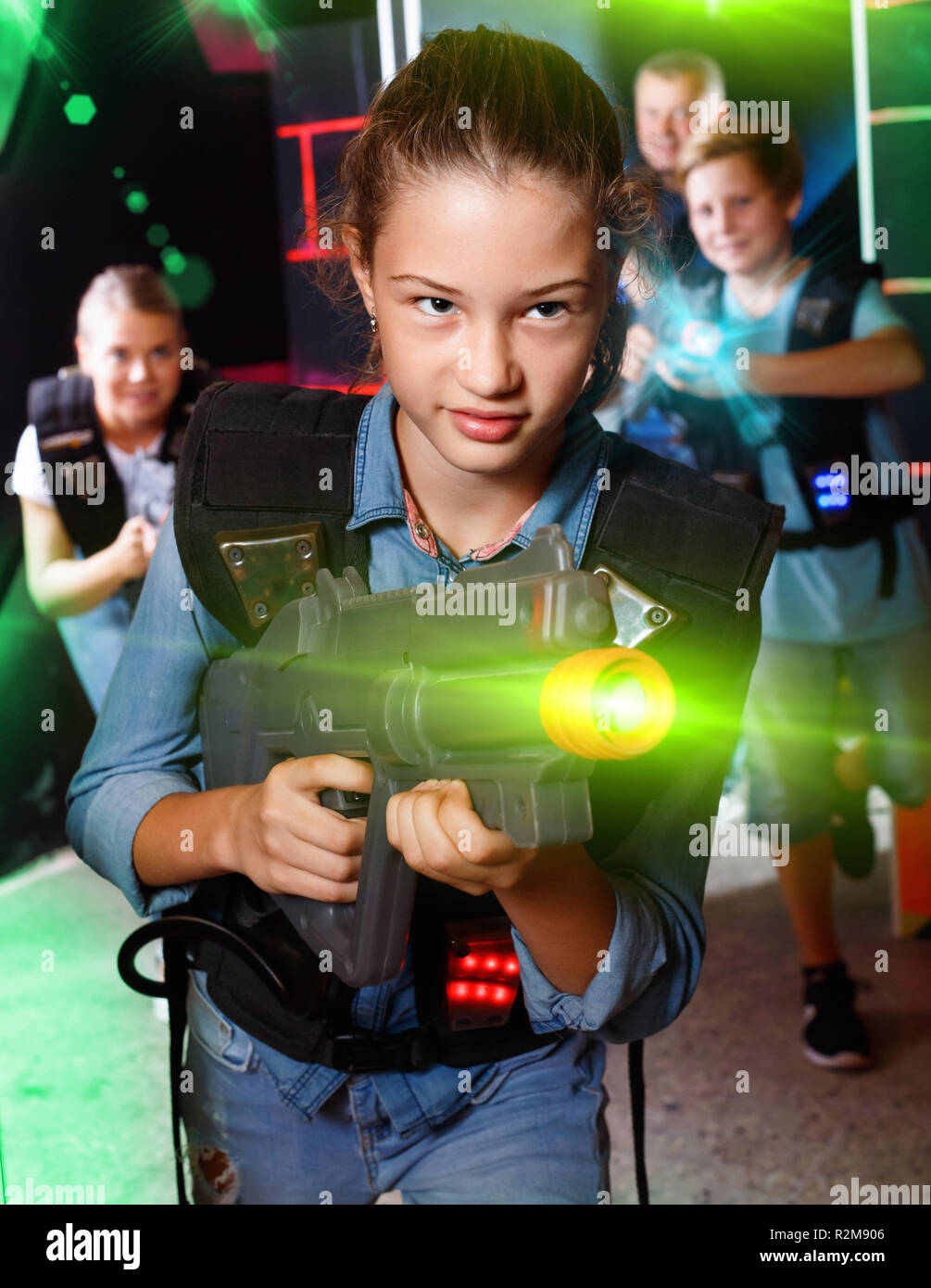 Portrait of glad teenager girl with laser gun having fun with her