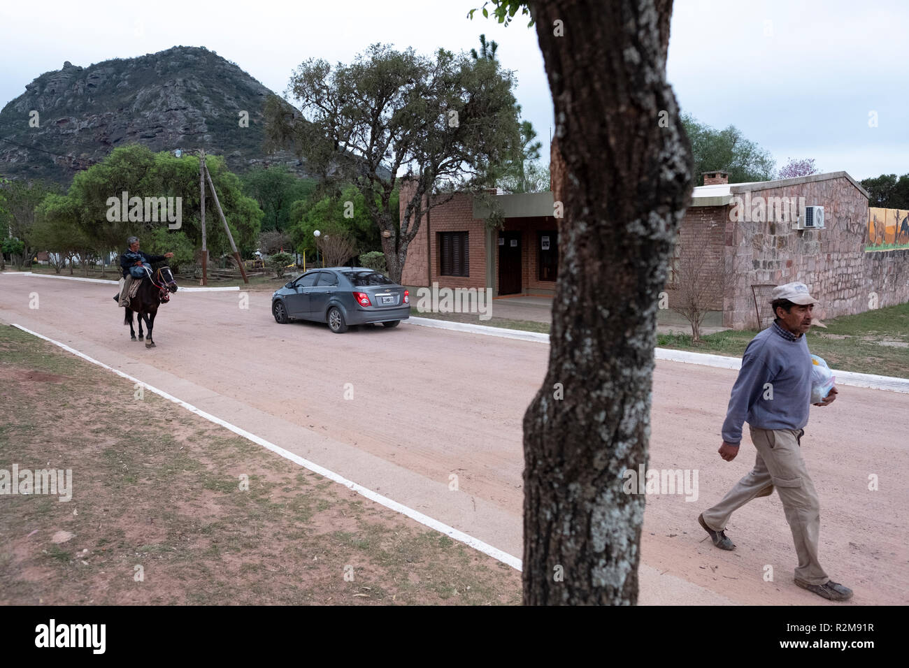 A horse rider and a pedestrian travel through the small village of Cerro Colorado in Córdoba, Argentina Stock Photo