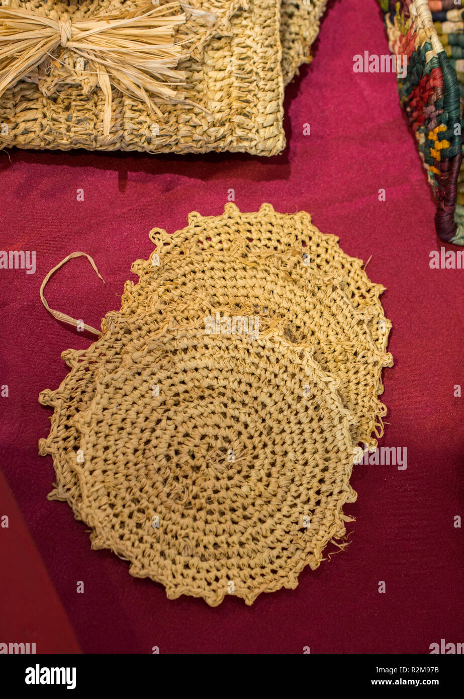 Four straw trivets on a red background on display Stock Photo - Alamy