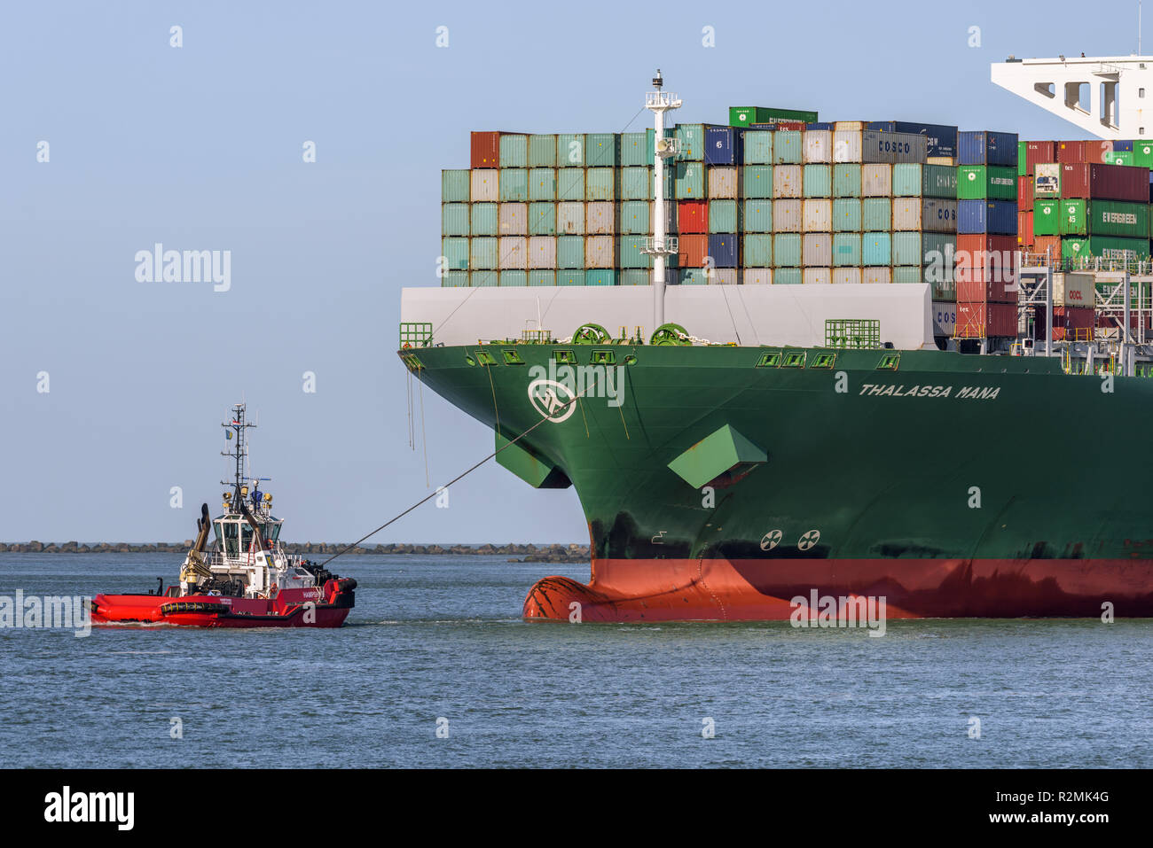 ROTTERDAM, THE NETHERLANDS - FEBRUARY 16, 2018: The large container ship Thalassa Mana is escorted by a tug at its arrival at the Maasvlakte, Port of  Stock Photo