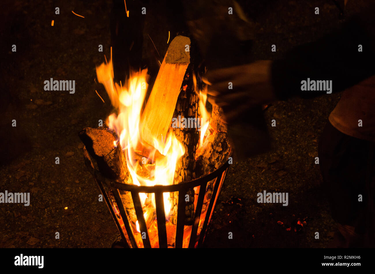 Fireplace of iron with burning logs during a cold evening for warmth. One puts on another log. Stock Photo