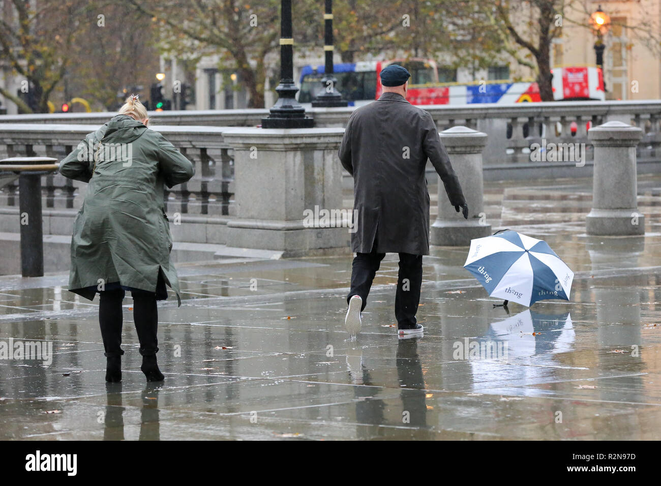 A man is seen running after an umbrella during a heavy rainfall.  According to The Met Office, snow and sleet is forecasted in Britain this week as temperatures plummet. Stock Photo