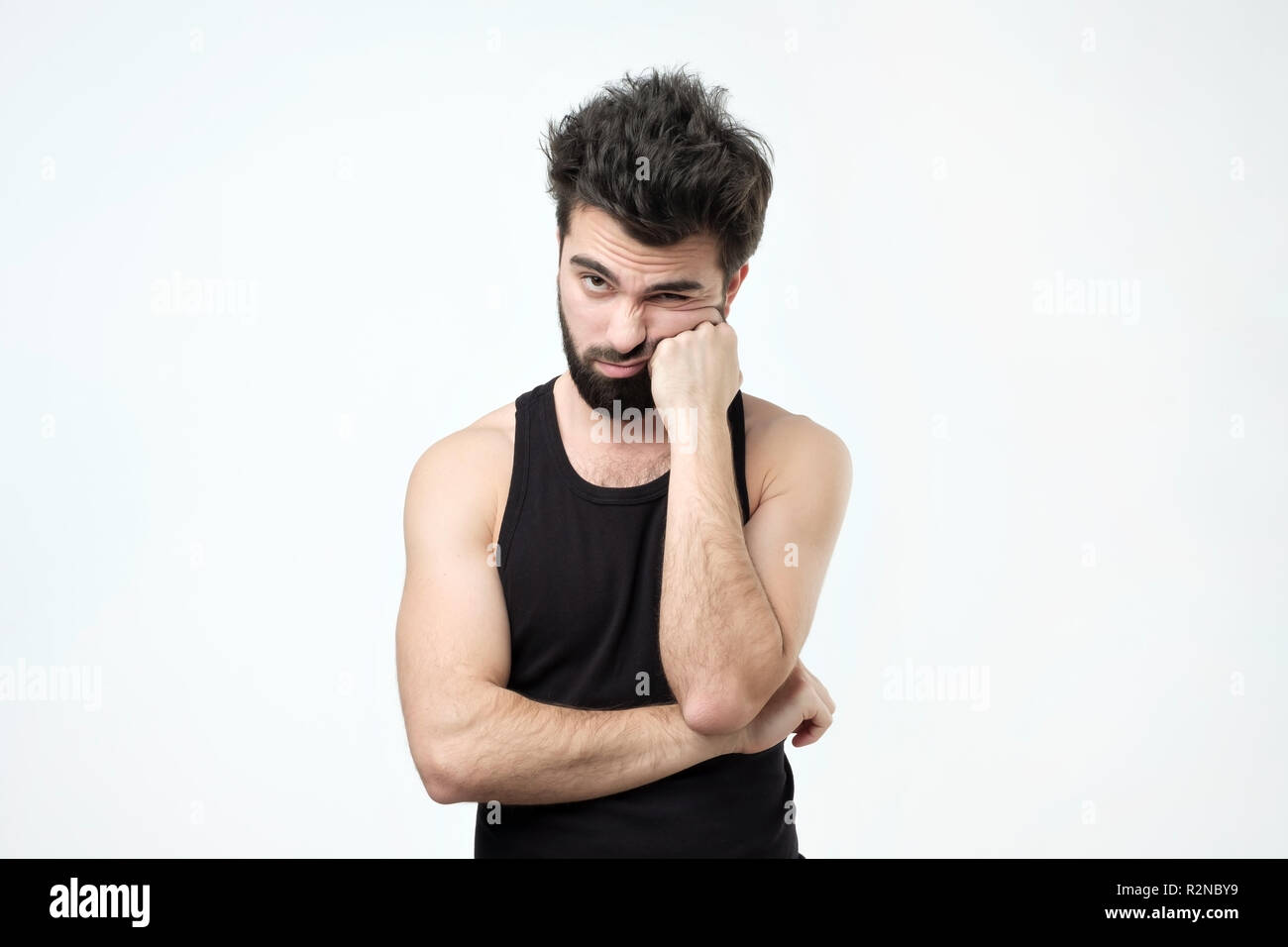Tired hispanic guy with beard, being exhausted and wanting to get rest against gray background Stock Photo