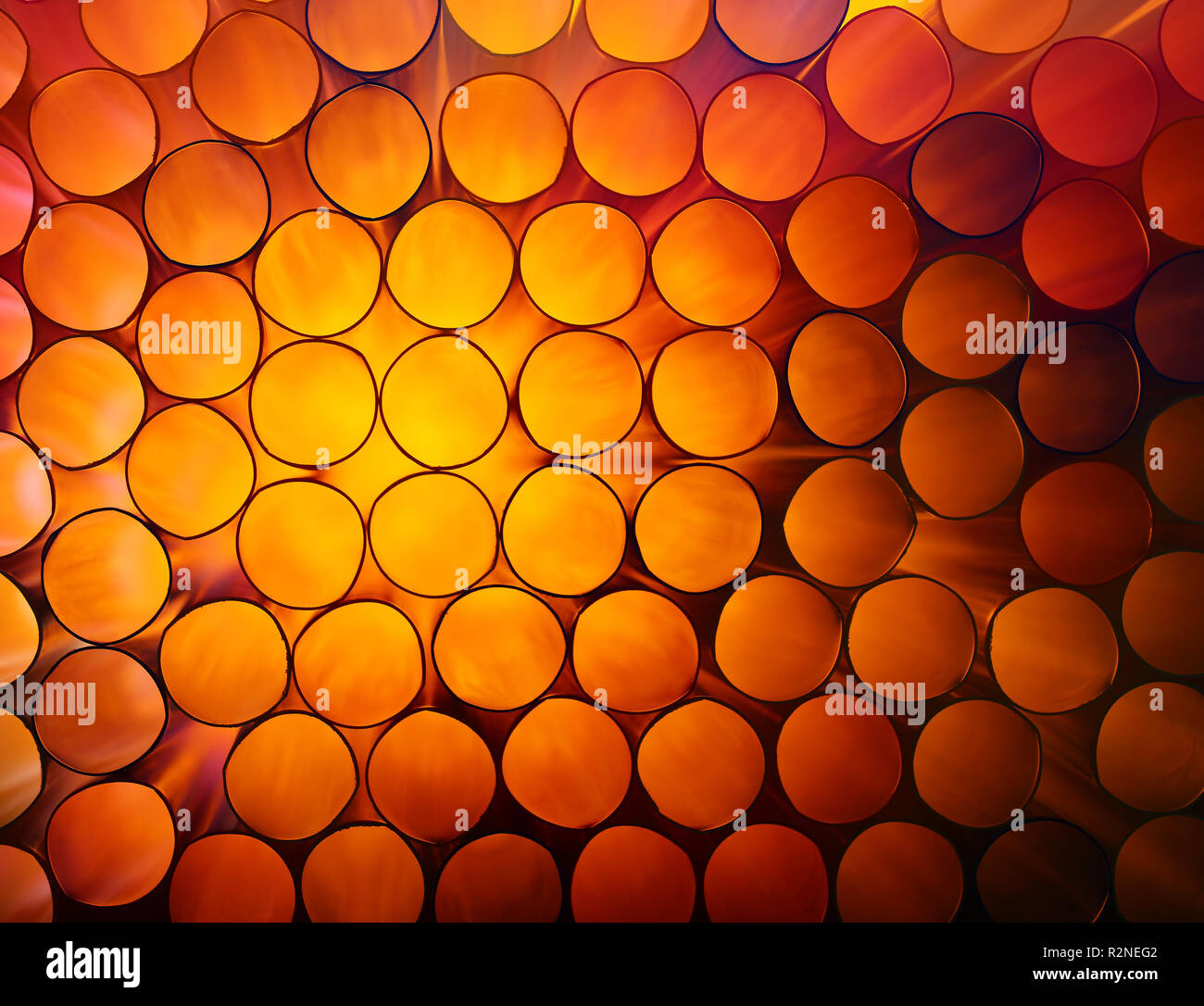 Abstract warm red and orange toned vivid colorful background texture of backlit stack drinking straw circles Stock Photo