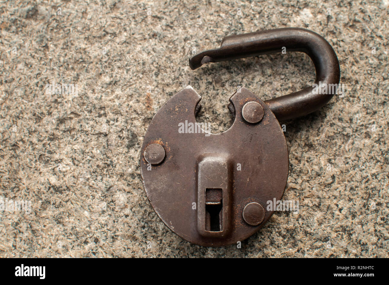Old weathered grunge retro open padlock closeup on solid stone surface background Stock Photo