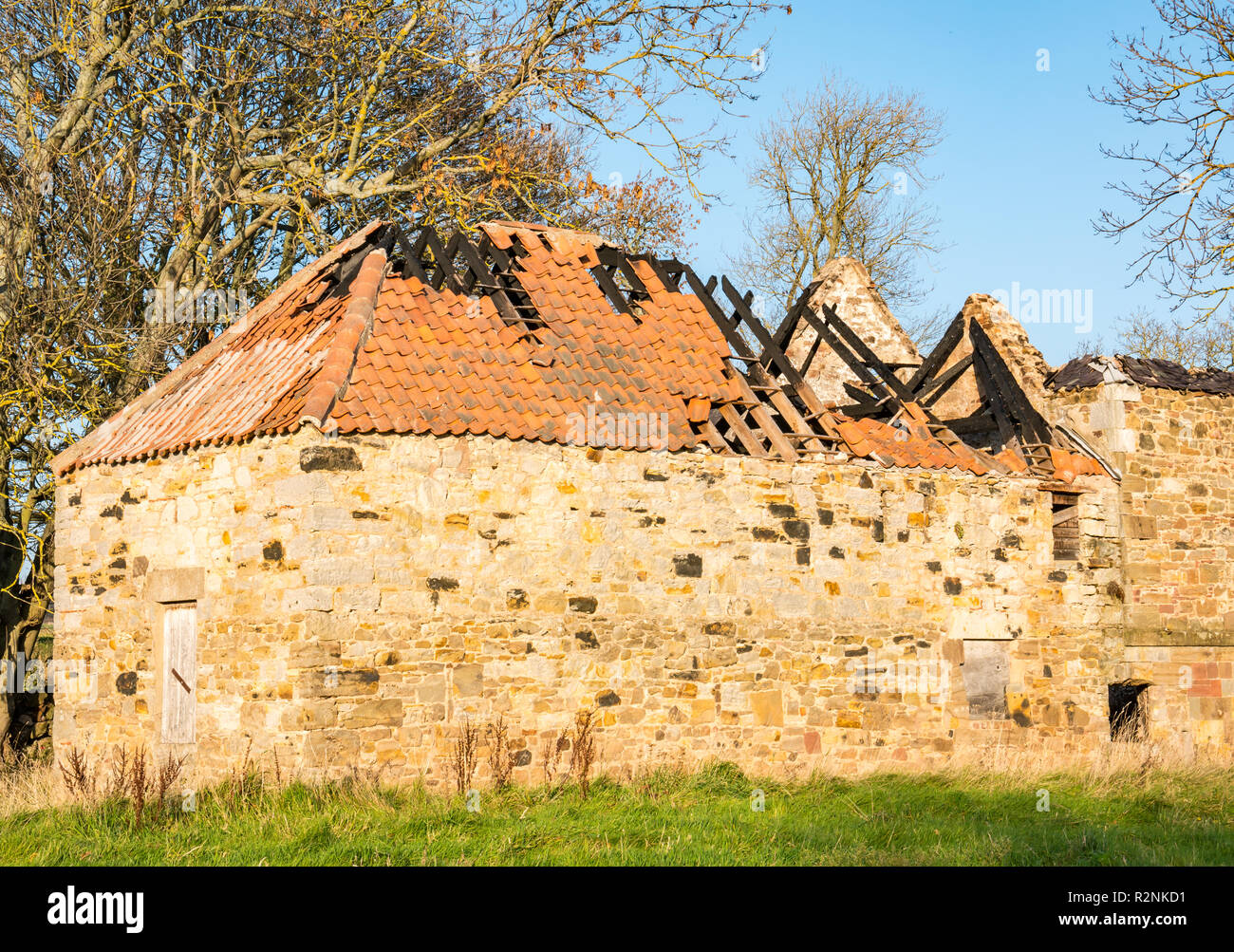 Abandoned stone building in field with collapsed  tiled roof showing fire damage along Tyne River, East Lothian, Scotland, UK Stock Photo