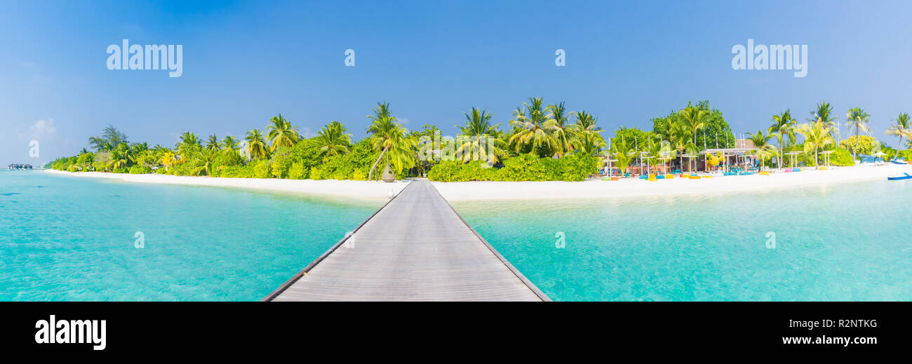 Amazing Maldives luxury island panorama. Beautiful beach scene with palm trees and perfect blue sea water. Relaxing and exotic tropical landscape view Stock Photo
