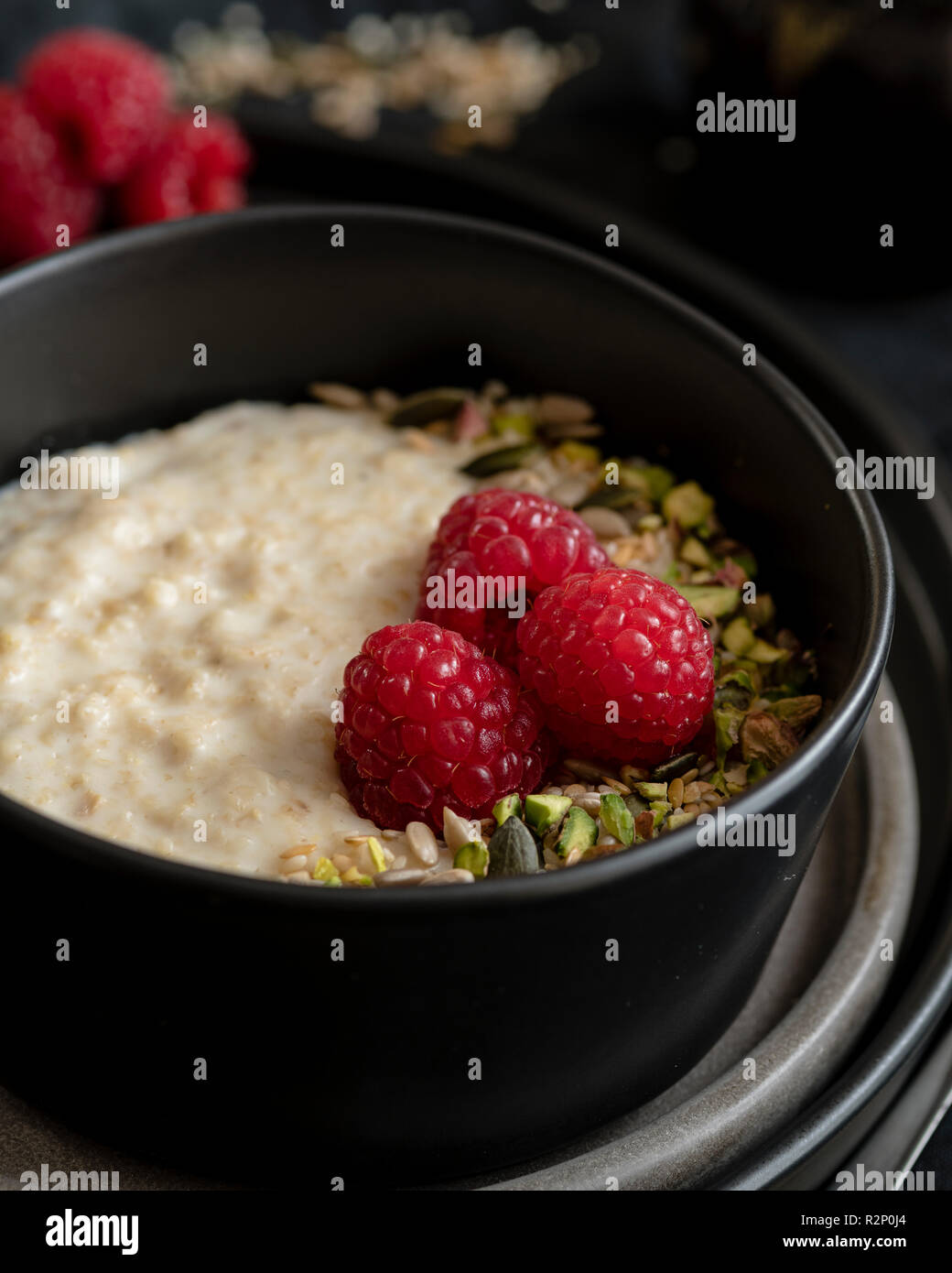 porridge in dark bowl with raspberry decoration Stock Photo