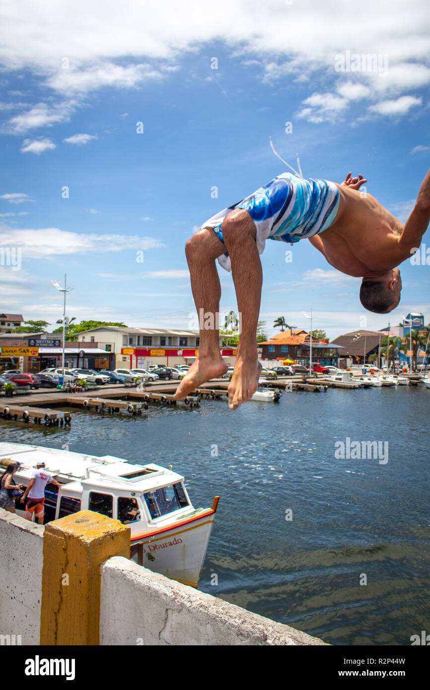 man jumps back somersault from a bridge at Lagoa da Conceição, Florianopolis, Brazil Stock Photo