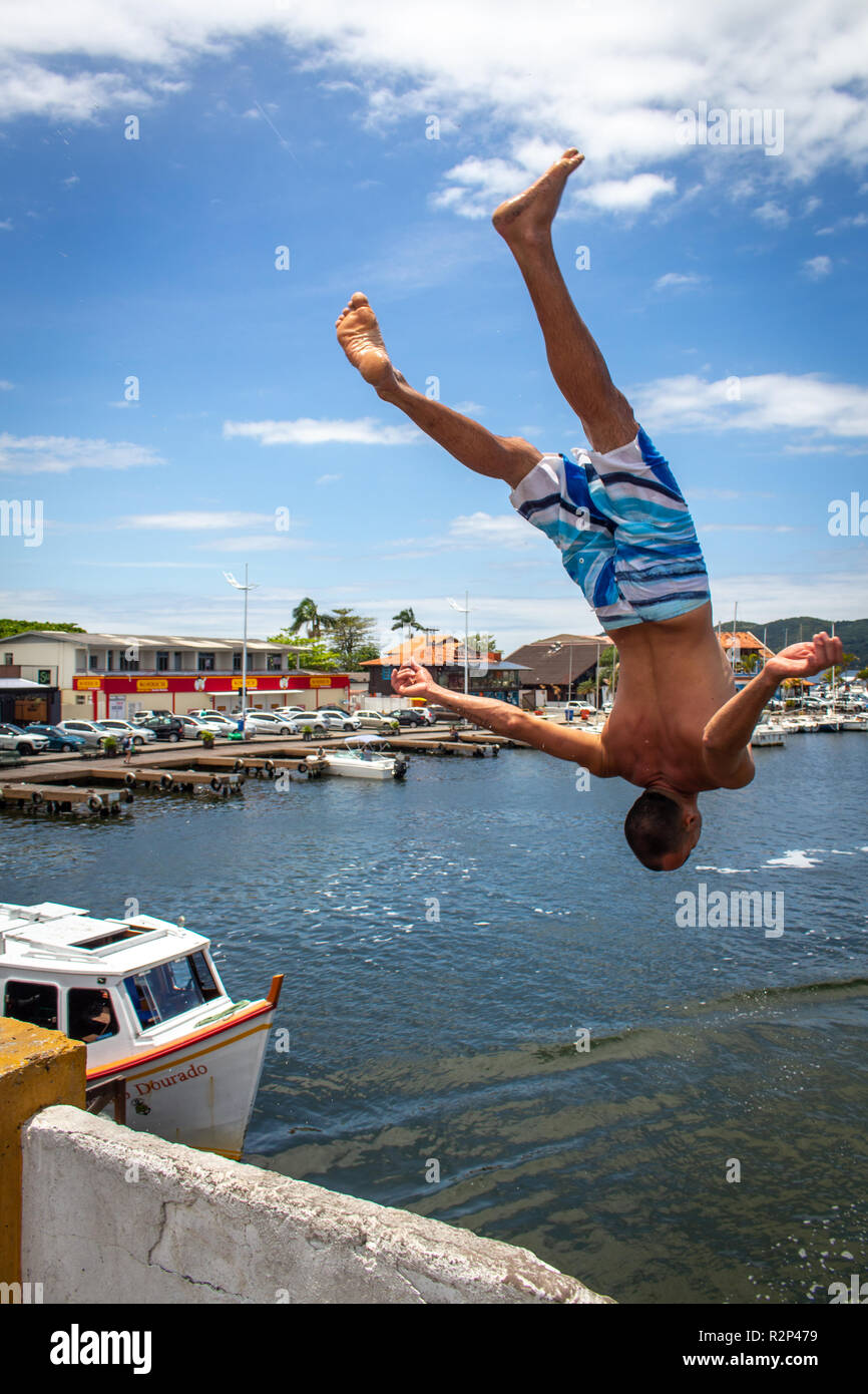 man jumps back somersault from a bridge at Lagoa da Conceição, Florianopolis, Brazil Stock Photo