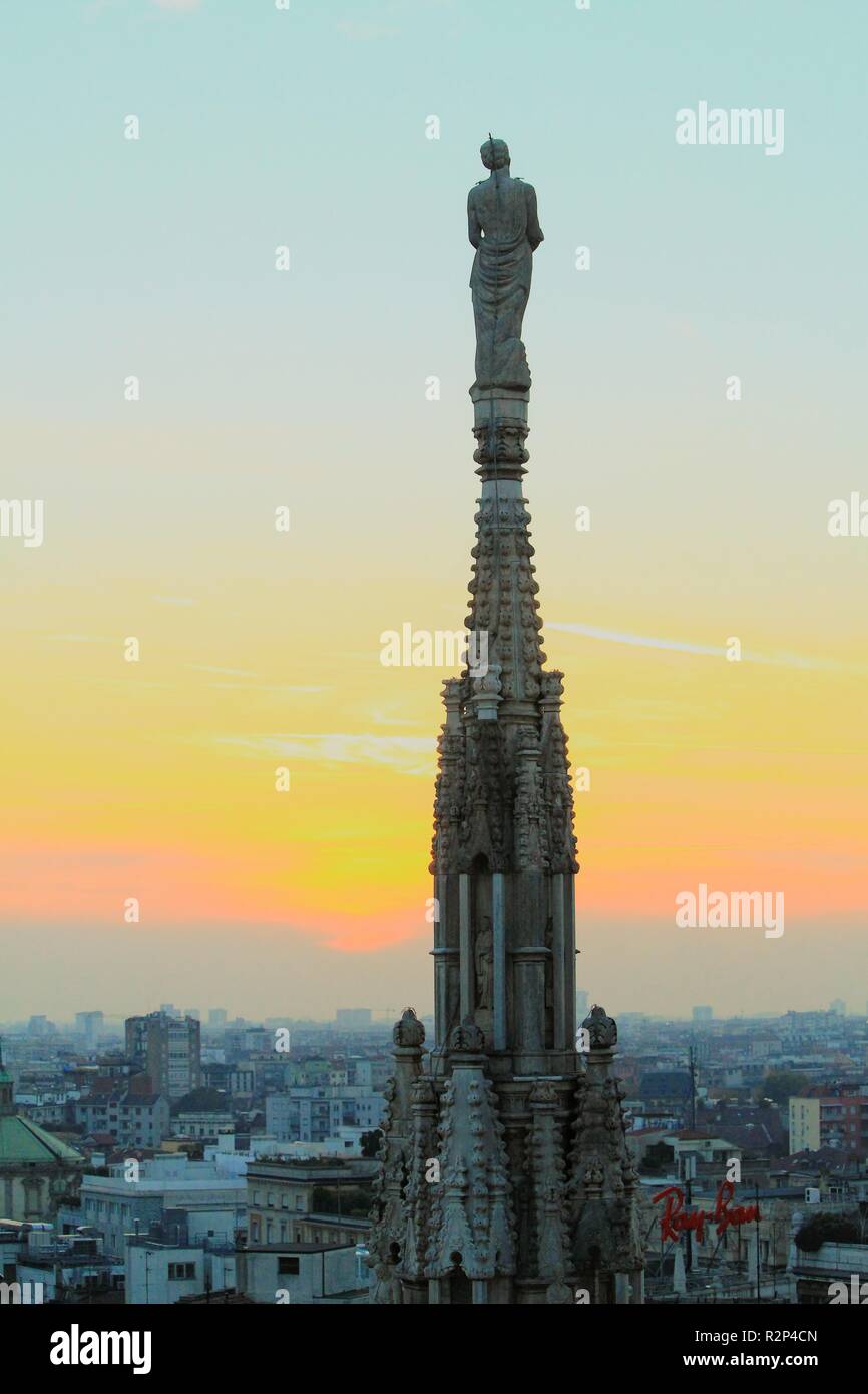saint statue of cathedral duomo milan over the skyline and sunset of