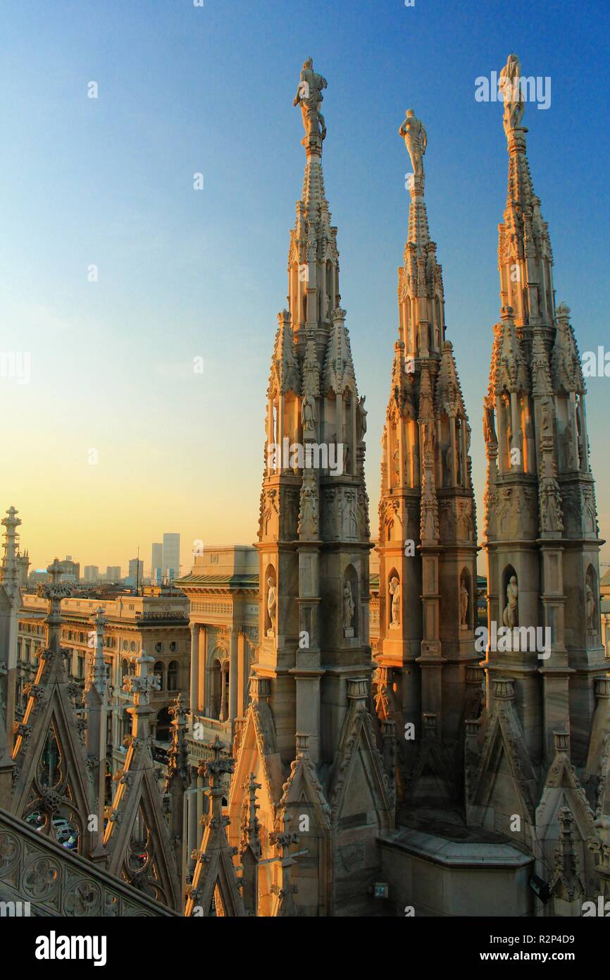 towers of catolic chathedral duomo milan with lights of sunset over it at Milan, Italy Stock Photo