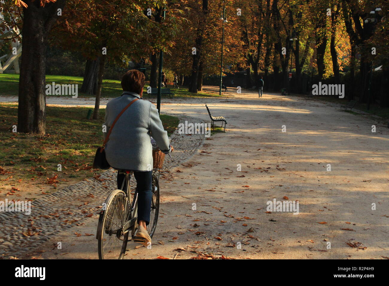 Woman rides a bike along the Sempione Park during autumn day at Sempione Park, Milan, Italy Stock Photo