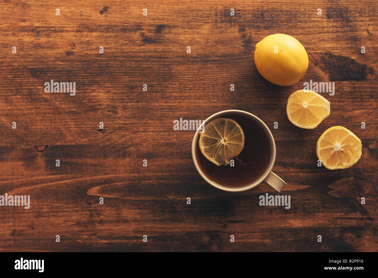 Cup of tea and fresh lemon, top view of the table with hot beverage with nostalgic retro tone Stock Photo