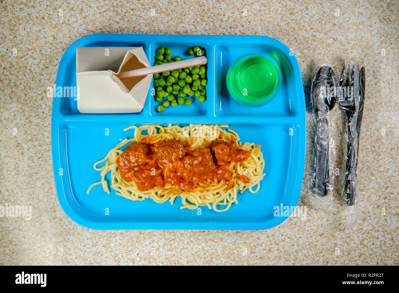 Grade school lunch tray of Italian spaghetti and meatballs with green peas milk carton and gelatin Stock Photo