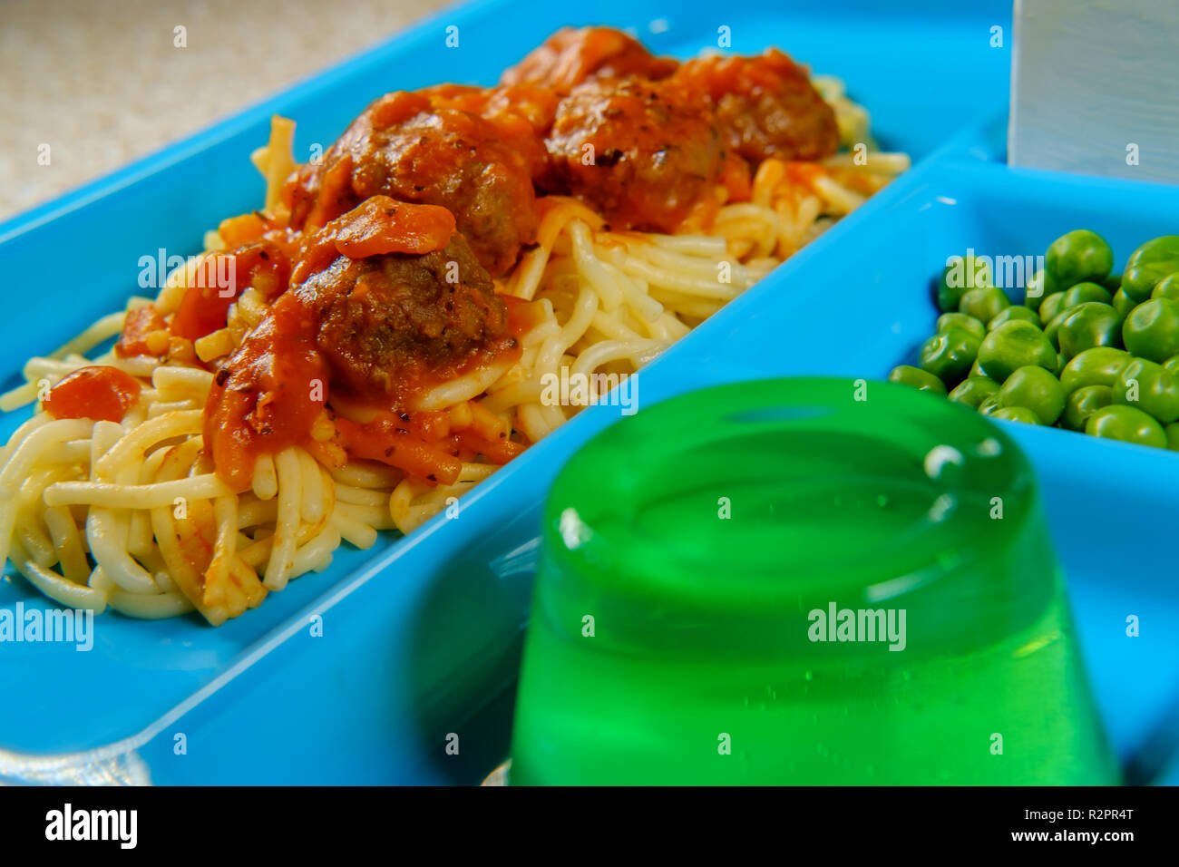 Grade school lunch tray of Italian spaghetti and meatballs with green