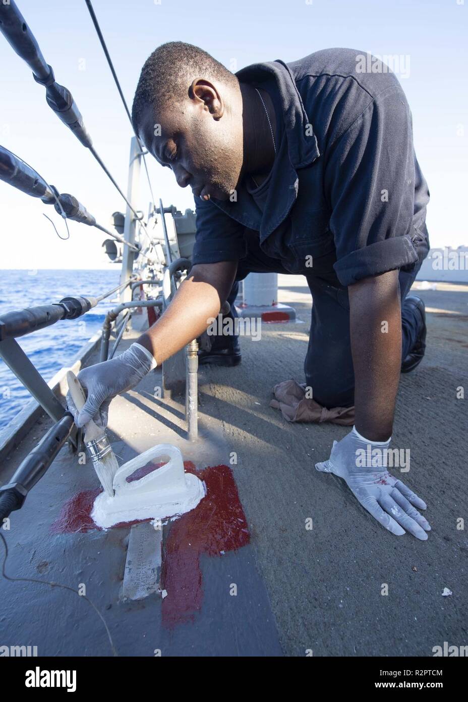 MEDITERRANEAN SEA (Oct. 29, 2018) Seaman Eyatom Pini paints a deck fixture aboard the Arleigh Burke-class guided-missile destroyer USS Arleigh Burke (DDG 51) in the Mediterranean Sea Oct. 29, 2018. Arleigh Burke, homeported at Naval Station Norfolk, is conducting naval operations in the U.S. 6th Fleet area of operations in support of U.S. national security interests in Europe and Africa. Stock Photo