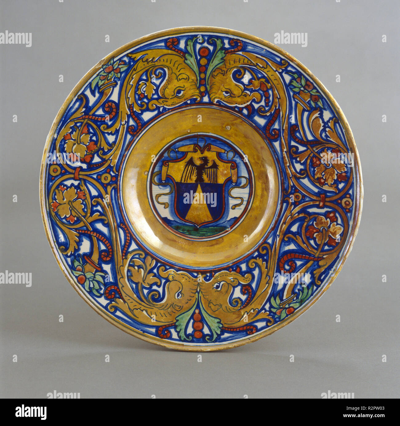 Plate with border of foliate scrollwork with dolphin heads and cornucopias; in the center, shield of arms of Vigerio of Savona. Dated: 1524. Dimensions: overall (diameter): 36.5 cm (14 3/8 in.). Medium: tin-glazed earthenware (maiolica). Museum: National Gallery of Art, Washington DC. Author: Workshop of Maestro Giorgio Andreoli of Gubbio. Stock Photo