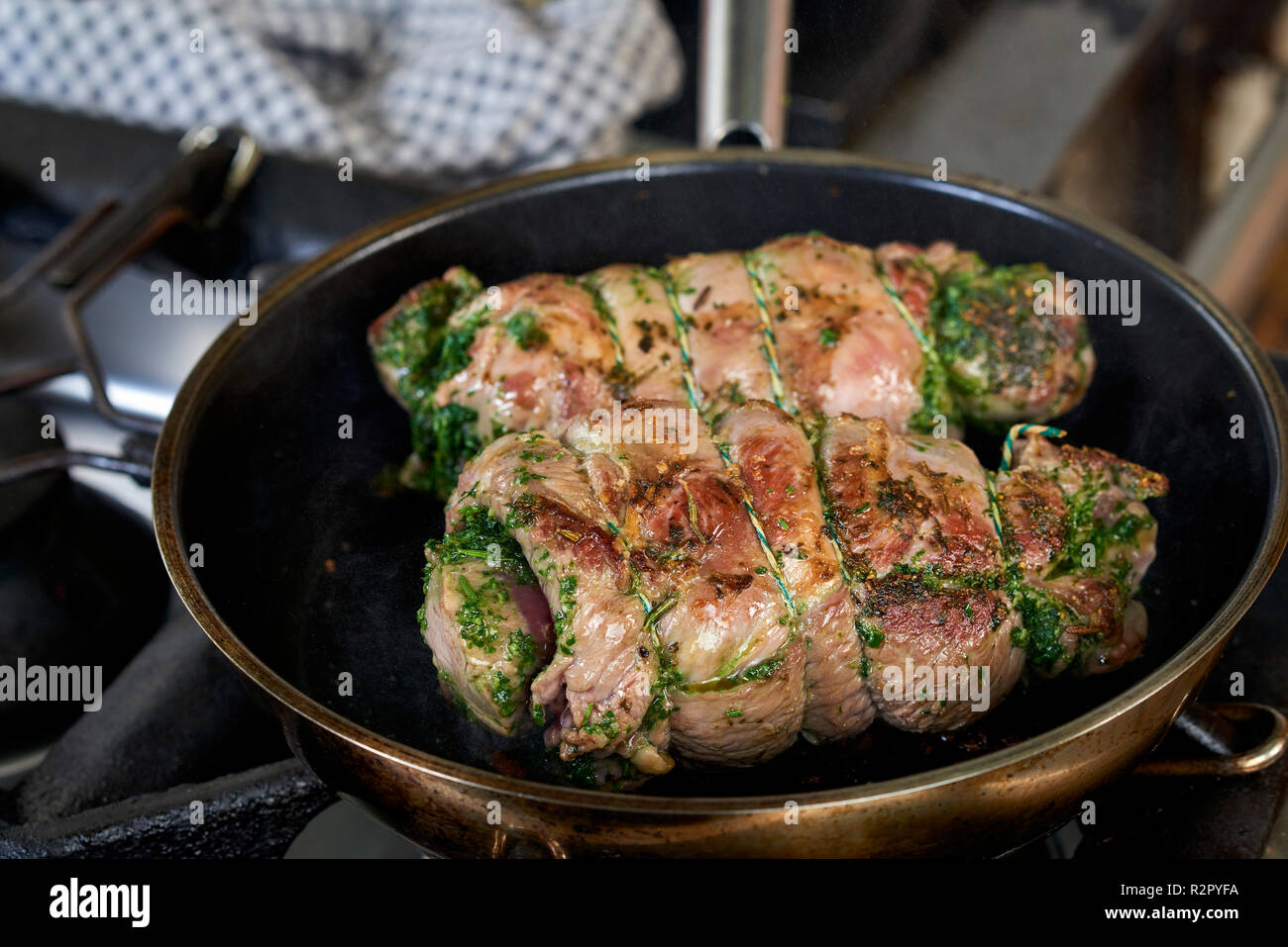 Photo series, step-by-step preparation of a leg of lamb filled with herbs and Provençal vegetables by using a food processor (Thermomix ® and Varoma ®), browning the leg of lamb in a pan Stock Photo