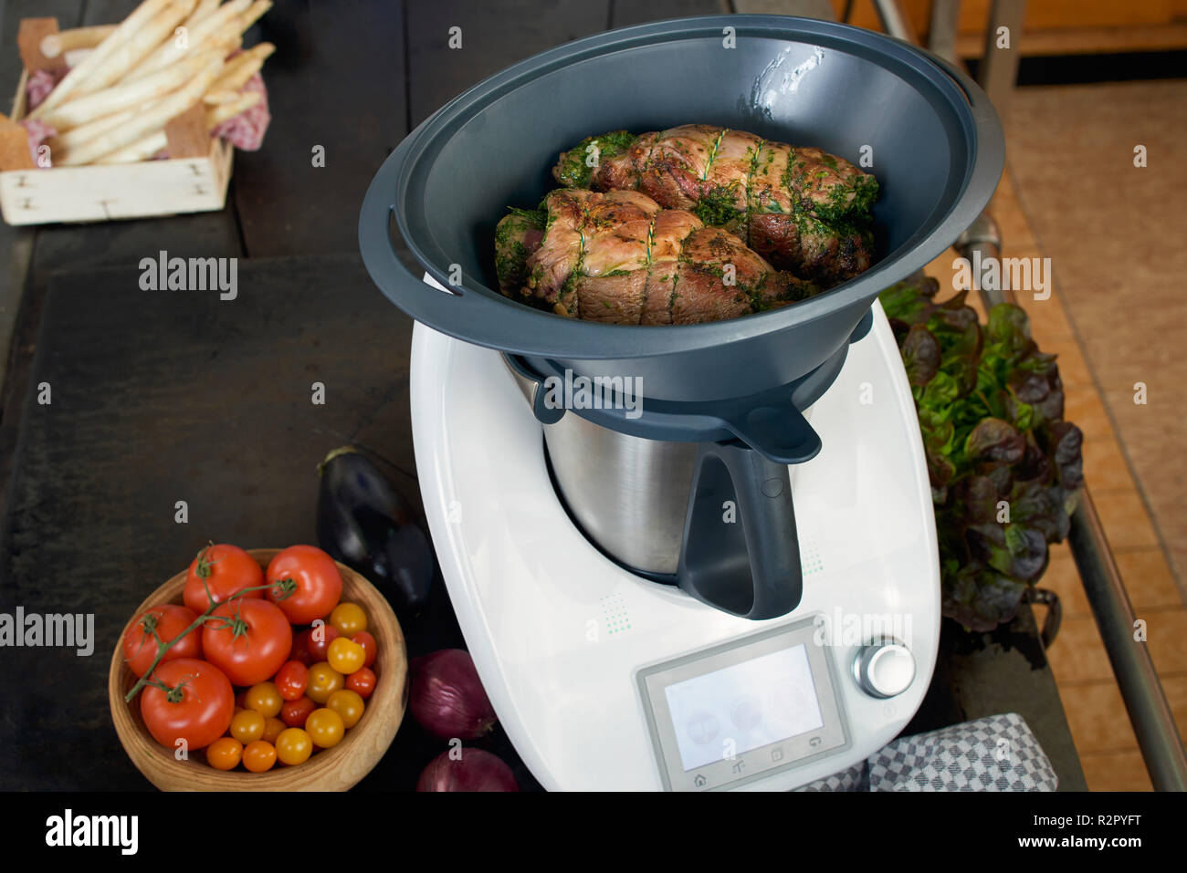 Photo series, step-by-step preparation of a leg of lamb filled with herbs  and Provençal vegetables by using a food processor (Thermomix ® and Varoma  ®), placing the leg of lamb in the