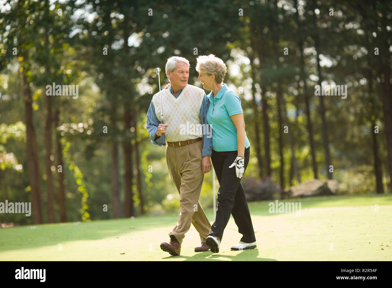 Older couple walking on golf course Stock Photo