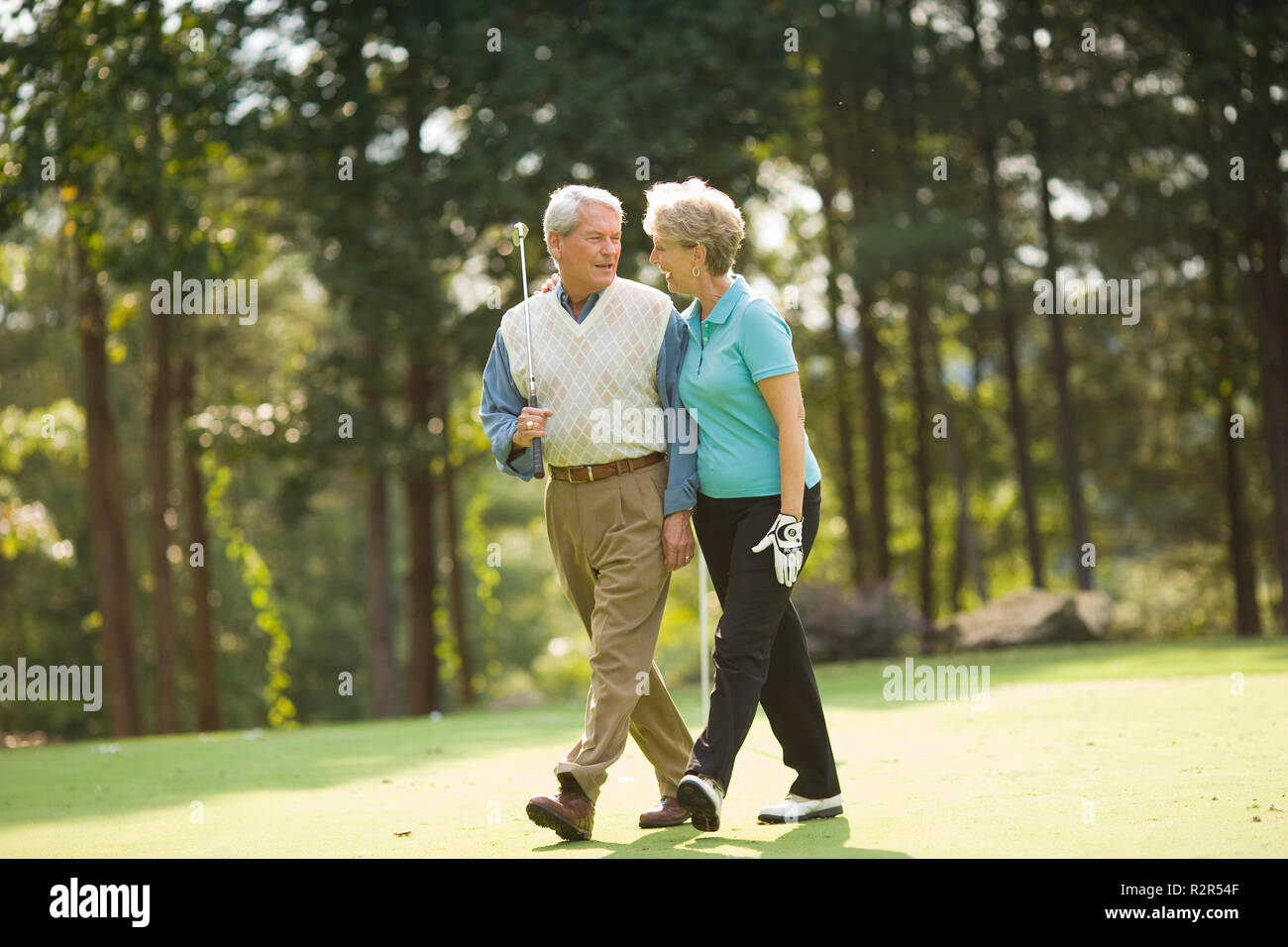 Older couple walking on golf course Stock Photo