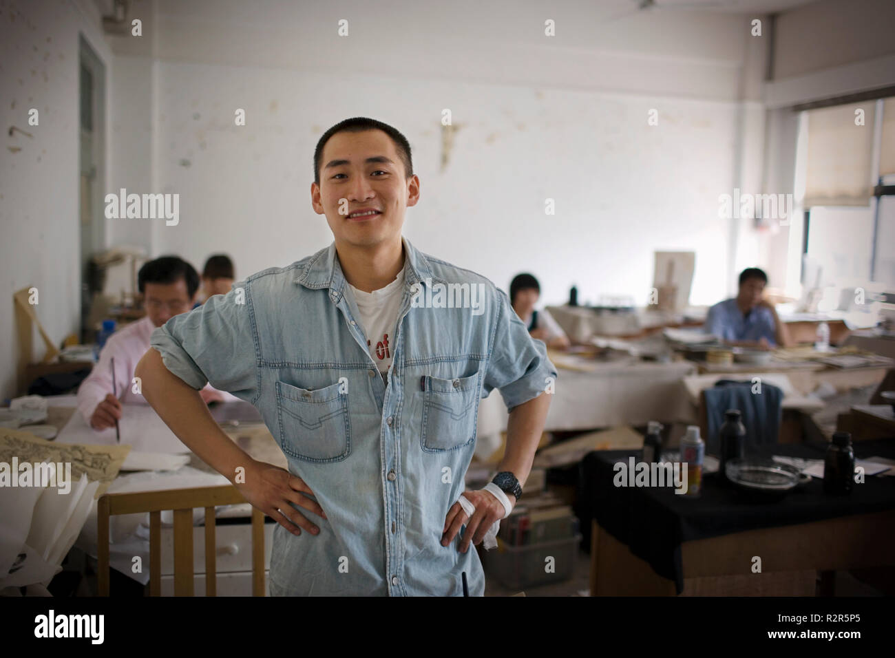 Portrait of a young adult man standing in an art classroom. Stock Photo