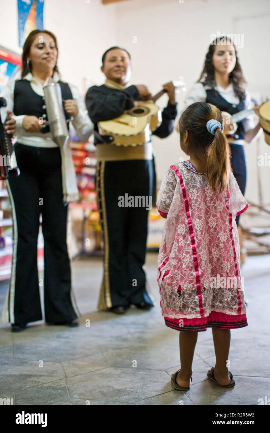 Young girl watching group of musicians playing their instruments inside a room. Stock Photo