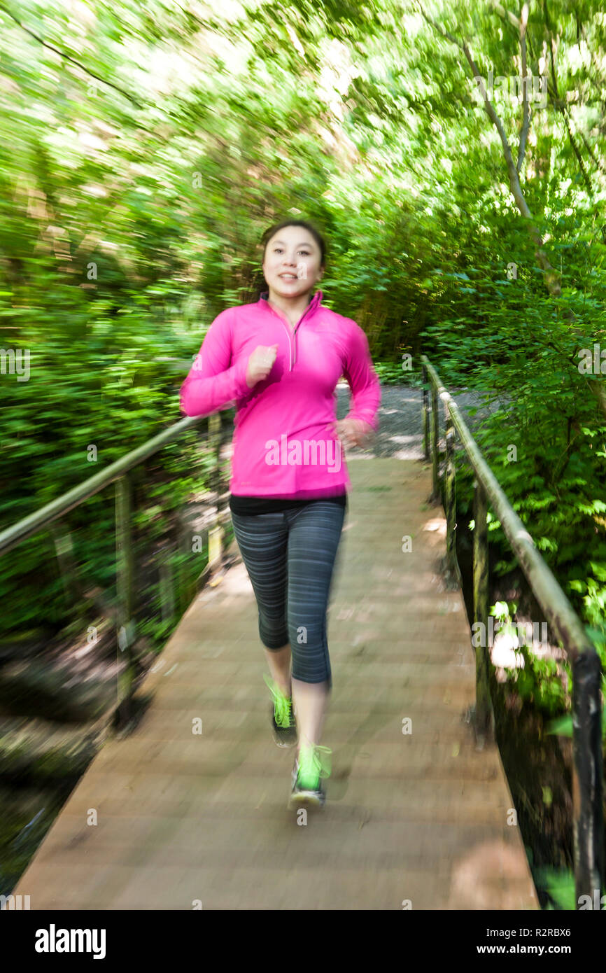 WA14617-00...WASHINGTON - Young asian woman jogging in an Edmonds City park. MR# S12 Stock Photo