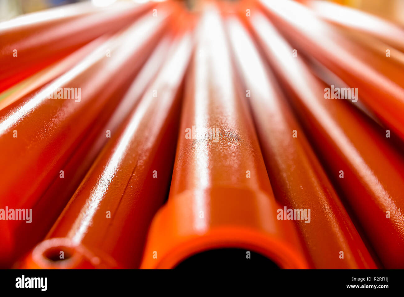 Metallic pipes covered with orange paint. Background with perspective. Selective focus. Close-up Stock Photo
