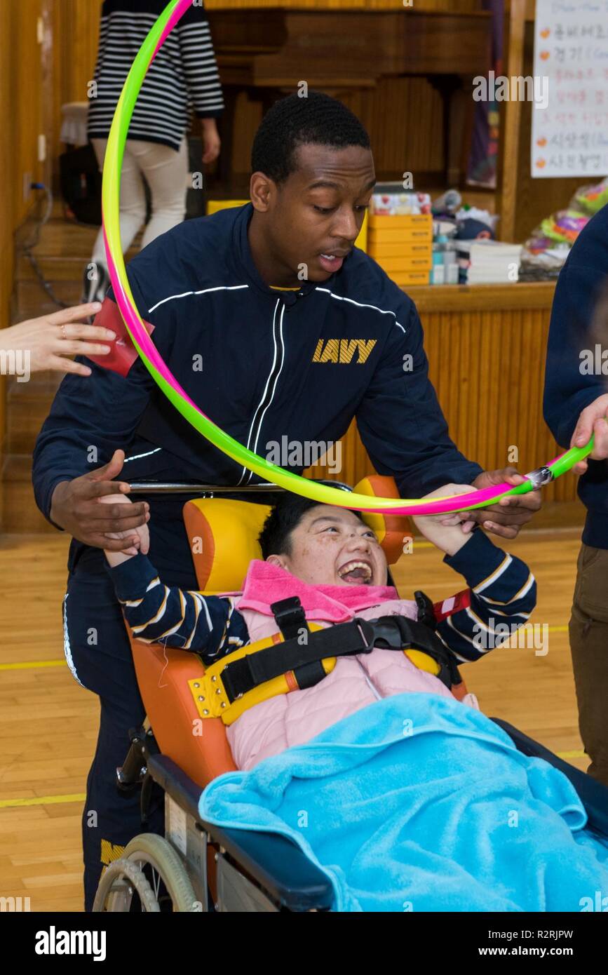 KOJE-DO, Republic of Korea (Nov. 03, 2018) Intelligence Specialist 3rd Class Langston Greer, assigned to Commander, U.S. Naval Forces Korea, participates in a community relations event with a resident of the Aikwangwon Home and School for the Mentally and Physically Disabled in Koje-do. The U.S. Navy and Aikwangwon community outreach program spans more than 60 years and began when U.S. Navy doctors and nurses assigned to the U.S. Navy base in Chinhae volunteered at the home during the Korean War. Stock Photo