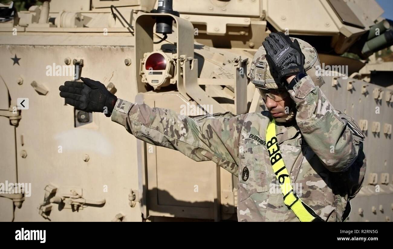 US Army Soldier Sgt. 1st Class Cedric Gustave assigned to 1st Armored Brigade Combat Team, 1st Cavalry Division’s, 91st Brigade Engineer Battalion ground guides a vehicle onto a flatbed during railhead operations in Karliki, Poland, November 6, 2018. 91st BEB combat engineers along with other members of the 1st Cavalry Division are relocating from various points throughout Eastern Europe as Atlantic Resolve in Europe continues. Stock Photo