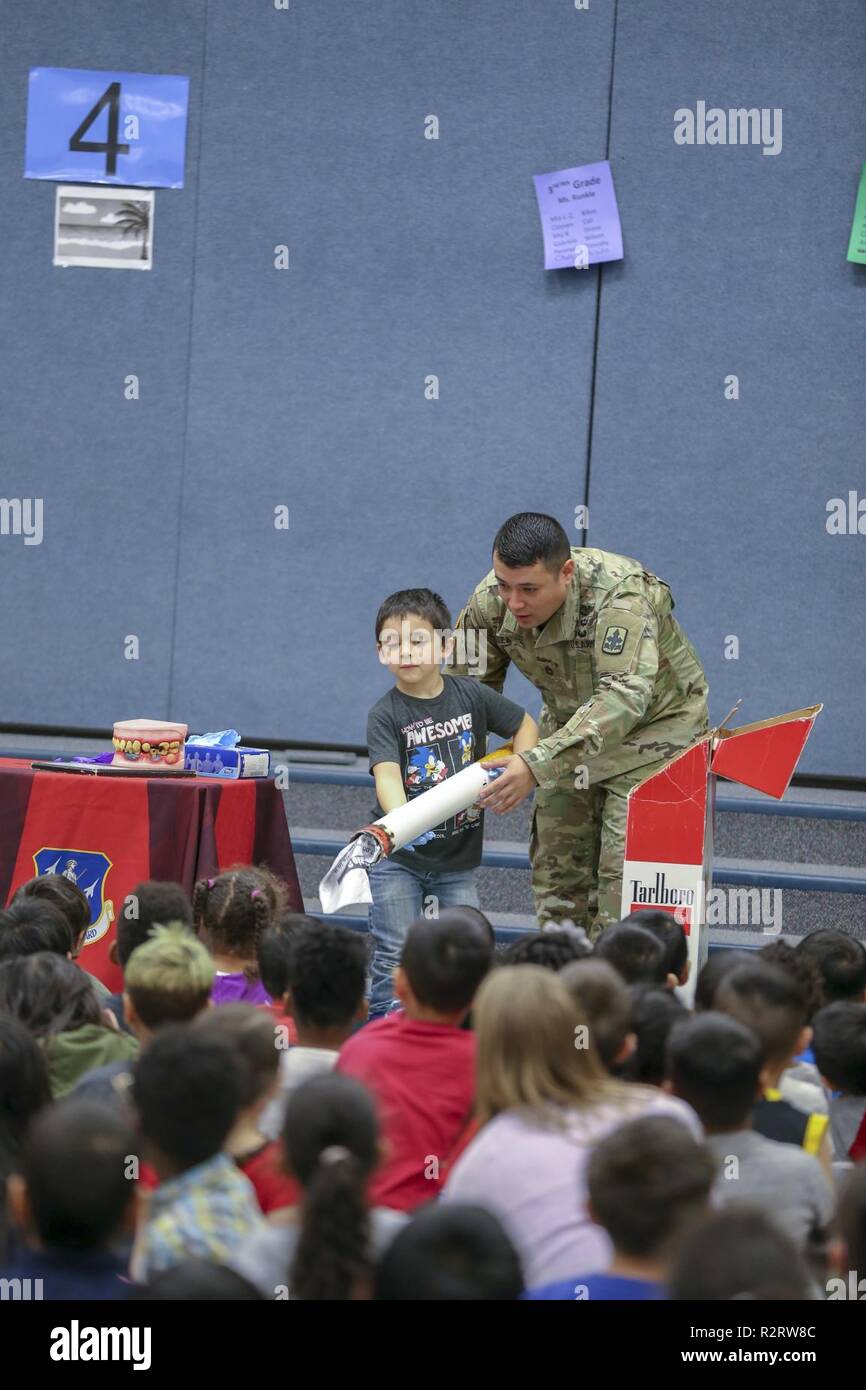Sgt. 1st Class Oliver Meza, Army National Guard drug testing coordinator, and his student assistant display a 5-foot fake cigarette with a list of up to 7,000 chemicals in cigarettes that are harmful during a Red Ribbon Week drug free celebration at Muldoon Elementary School, October 29, 2018.  The event brought multiple law enforcement agencies together to promote a healthy and drug-free lifestyle by greeting students upon arrival at school, static displays of military and police vehicles, and a drug free message. Stock Photo