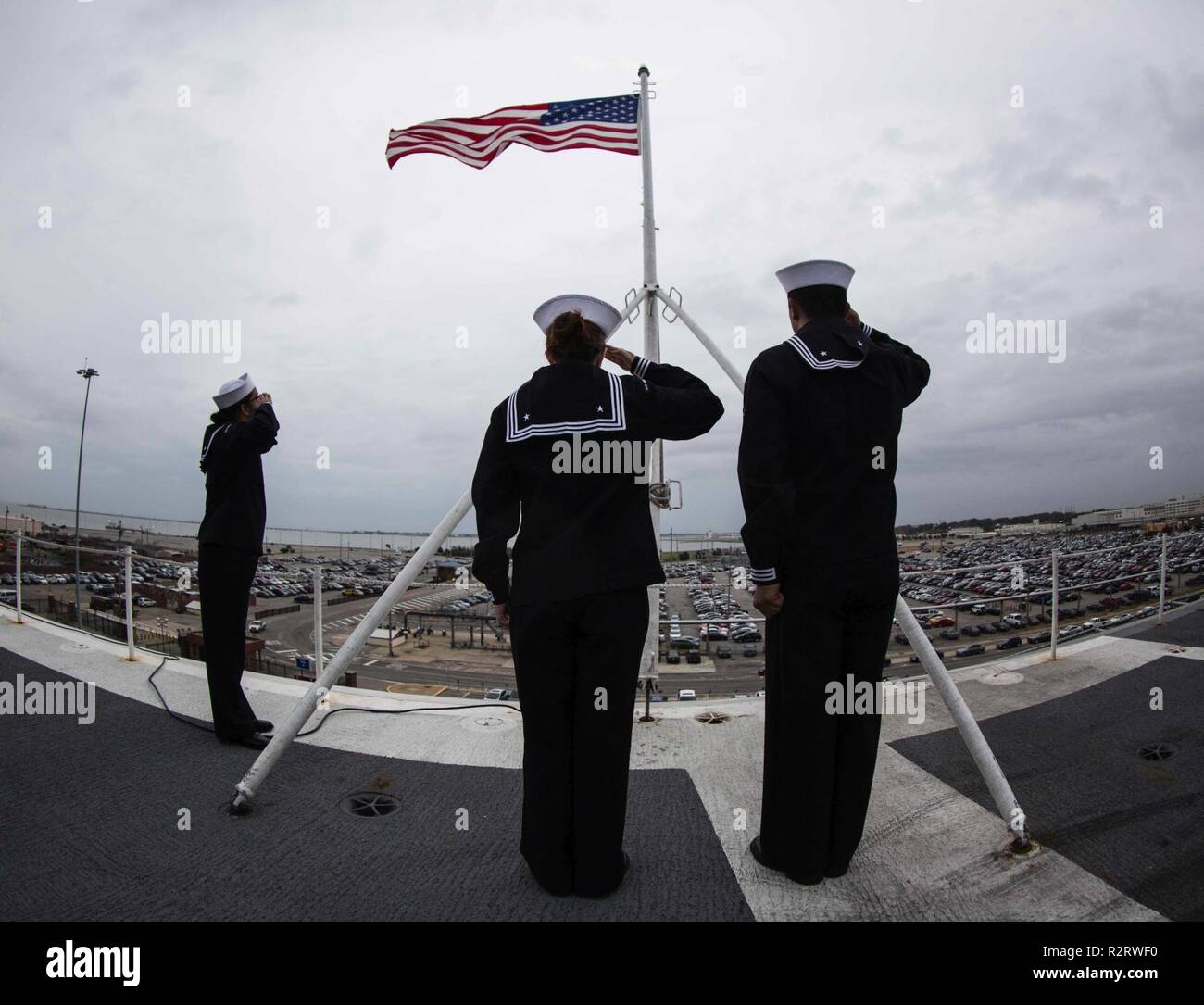 NORFOLK (Nov. 2, 2018) Sailors salute the national ensign aboard the Nimitz-class aircraft carrier USS Abraham Lincoln (CVN 72), Nov. 2, 2018. Stock Photo