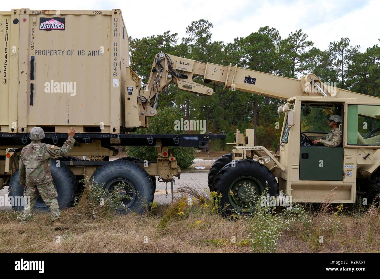 Spc. Steven Steedley (right), a 122nd Aviation Support Battalion, 82nd Combat Aviation Brigade, 82nd Airborne Division transportation specialist, moves a conex box with an All-Terrain Lifter, Army System II variable-reach forklift while Staff Sgt. Luis Gonzalez (left), a 122nd ASB, 82nd CAB, 82nd Abn. Div. transportation sergeant, ground guides on Nov. 1, 2018 at Fort Bragg, North Carolina. U.S. Northern Command is providing military support to the Department of Homeland Security and U.S. Customs and Border Protection to secure the southern border of the United States. Stock Photo