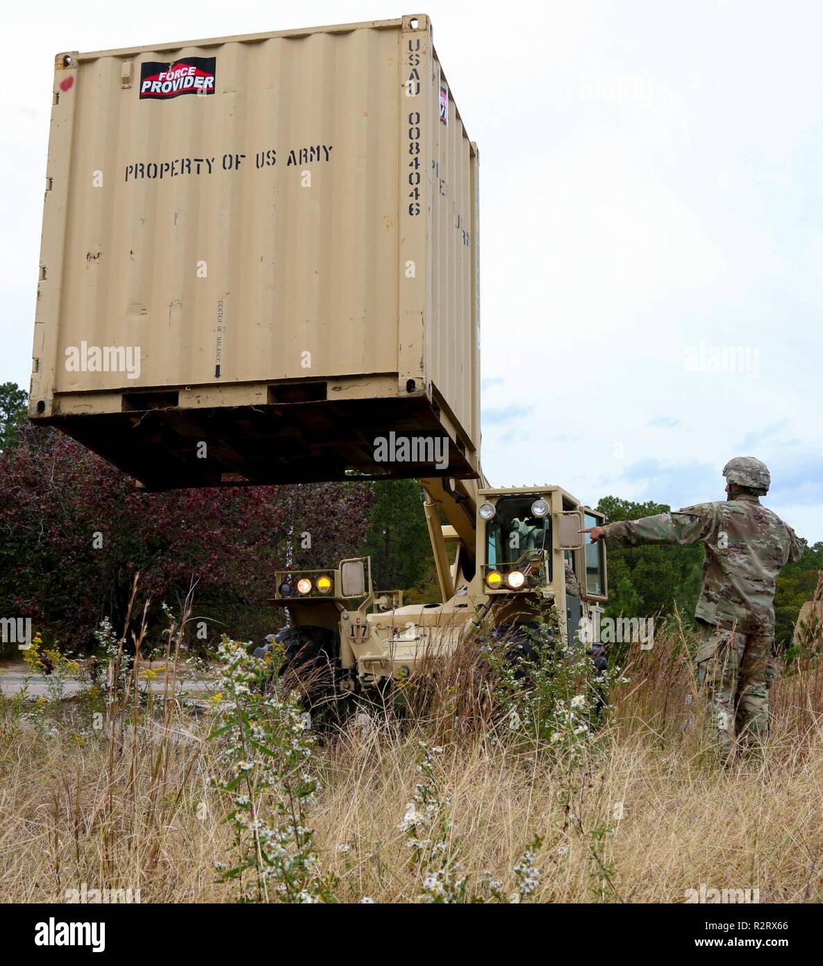 Spc. Steven Steedley (left), a 122nd Aviation Support Battalion, 82nd Combat Aviation Brigade, 82nd Airborne Division transportation specialist, moves a conex box with an All-Terrain Lifter, Army System II variable-reach forklift while Staff Sgt. Luis Gonzalez (right), a 122nd ASB, 82nd CAB, 82nd Abn. Div. transportation sergeant, ground guides on Nov. 1, 2018 at Fort Bragg, North Carolina. U.S. Northern Command is providing military support to the Department of Homeland Security and U.S. Customs and Border Protection to secure the southern border of the United States. Stock Photo