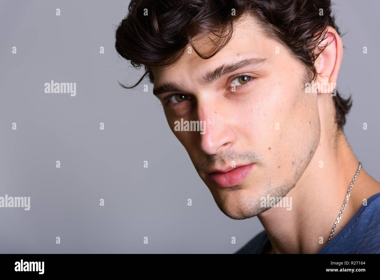 Close up of young handsome Hispanic man against gray background Stock Photo