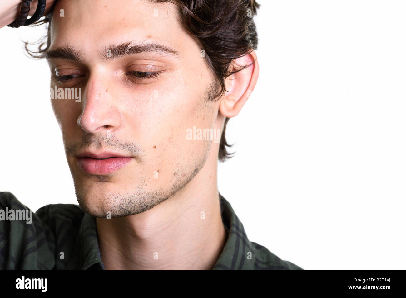 Close up of young handsome man brushing hair back while thinking Stock Photo