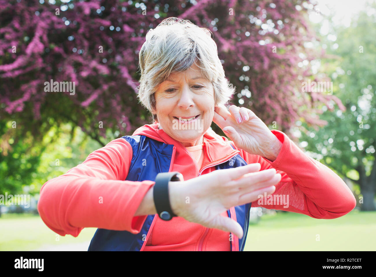 Active senior female runner checking smart watch in park Stock Photo