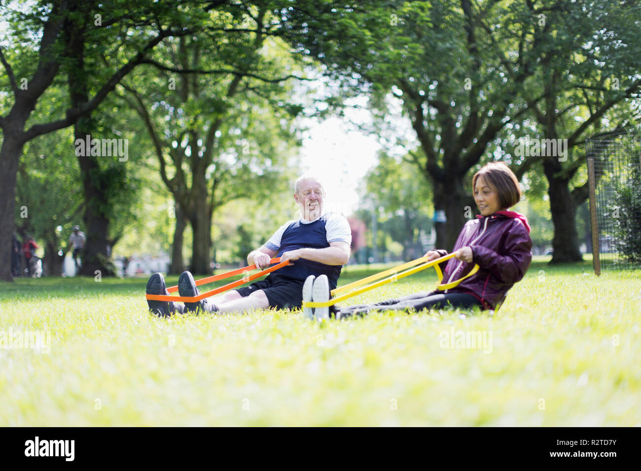 Active senior couple exercising, using resistance bands in park Stock Photo