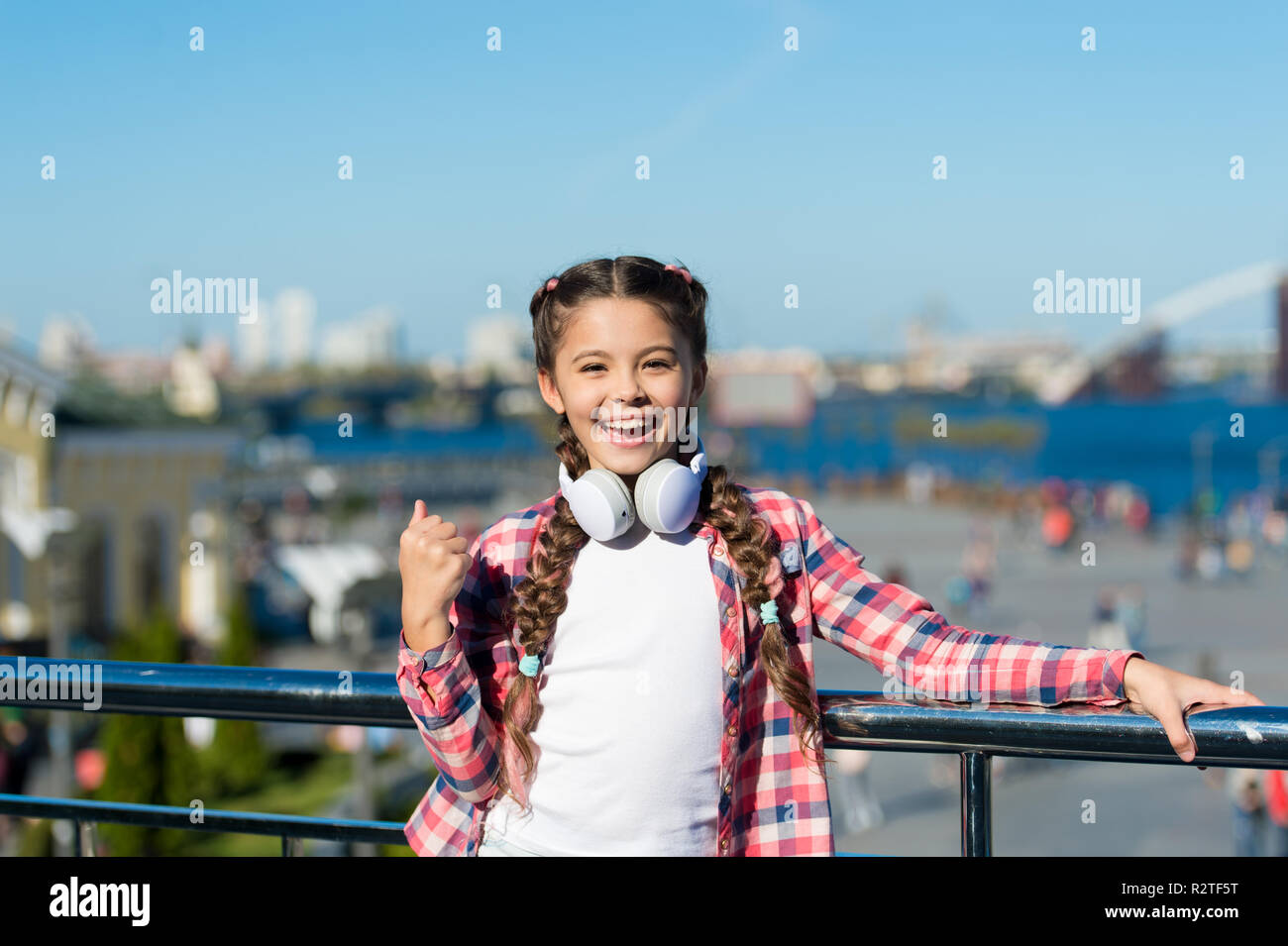 Girl child listen music outdoors with modern headphones. Listen for free. Stream music anywhere. Get music family subscription. Access to millions of songs. Best music apps that deserve a listen. Stock Photo